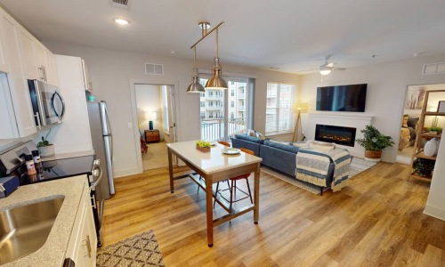 a kitchen and a living room with a tv, couch, tables and chairs